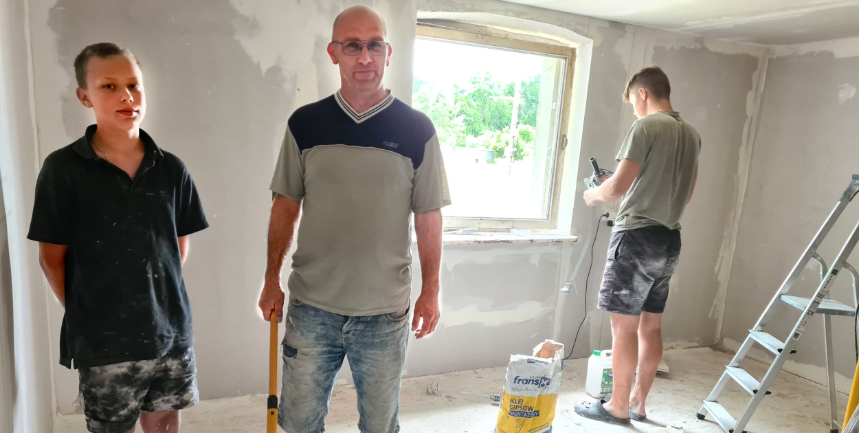 Na zdjęciu pan Rafał (w środku) razem z 14-letnim Krzysztofem (od lewej) pracują przy odmalowywaniu ścian w jednym z pokoi, pomagał im nastolatek z sąsiedztwa